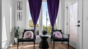 A room with two black chairs, a black table, purple curtains, and framed artwork on the wall. - Stylish Nashville Stay • Skyline Views (Nashville)