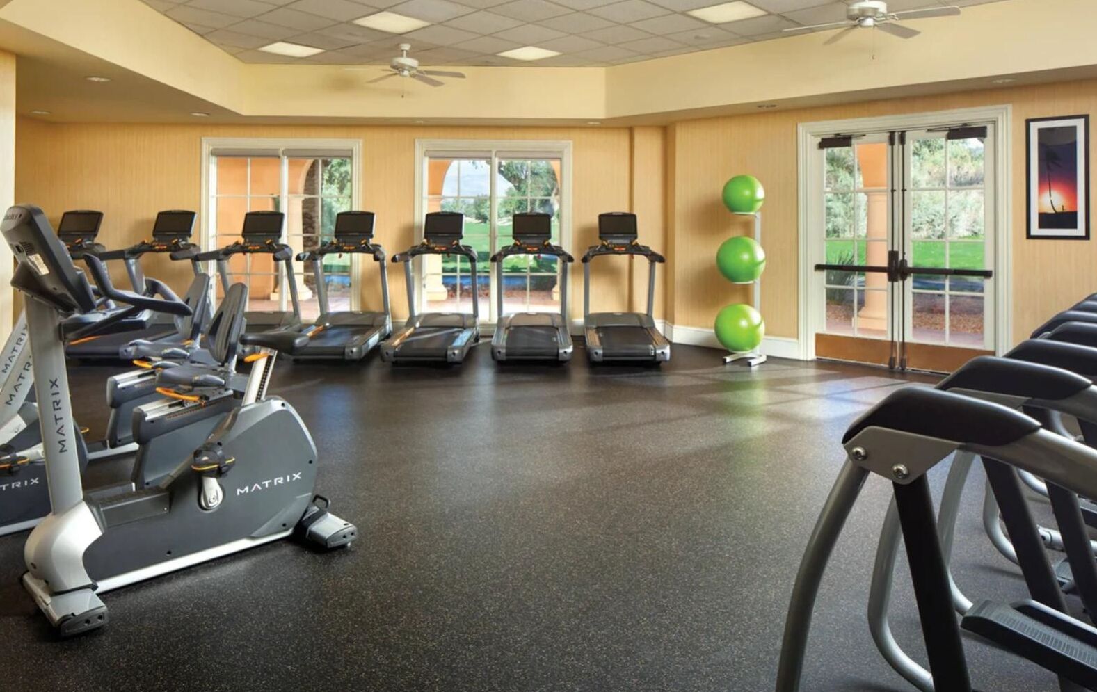Une salle de sport équipée de tapis de course, de vélos d’appartement et de ballons d’exercice.