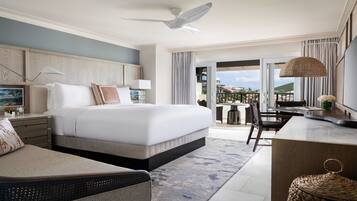 Une chambre d’hôtel équipée d’un lit, d’un bureau, d’une chaise, d’un balcon avec vue et d’un ventilateur de plafond.