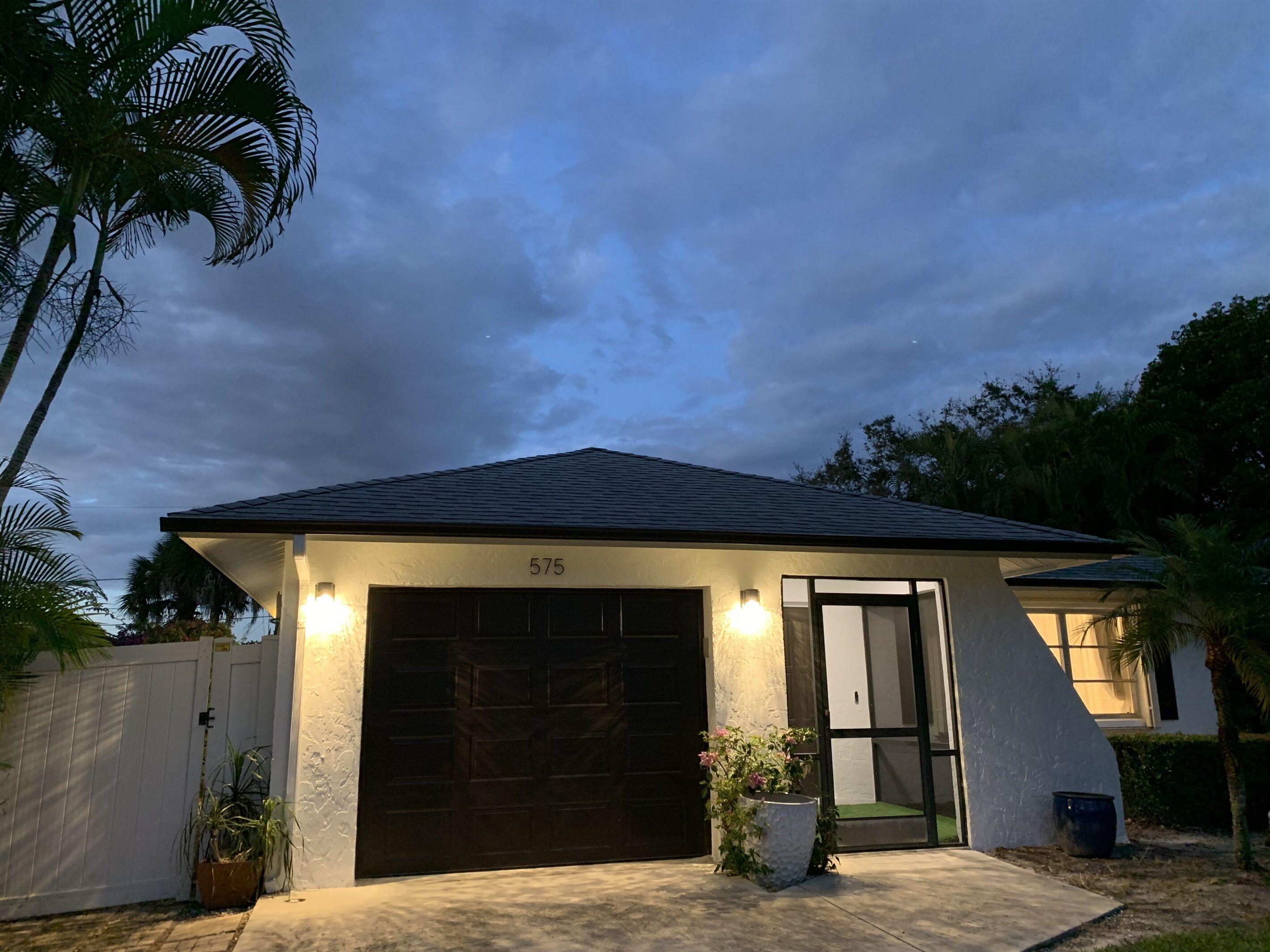 Ein Haus mit Garage, Nummer 575, einem weißen Zaun und einer Auffahrt zur Garage.