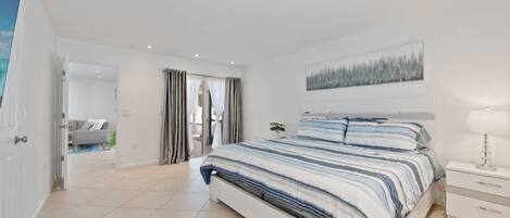 Un dormitorio moderno con una cama grande, una mesita de noche y un cuadro en la pared.