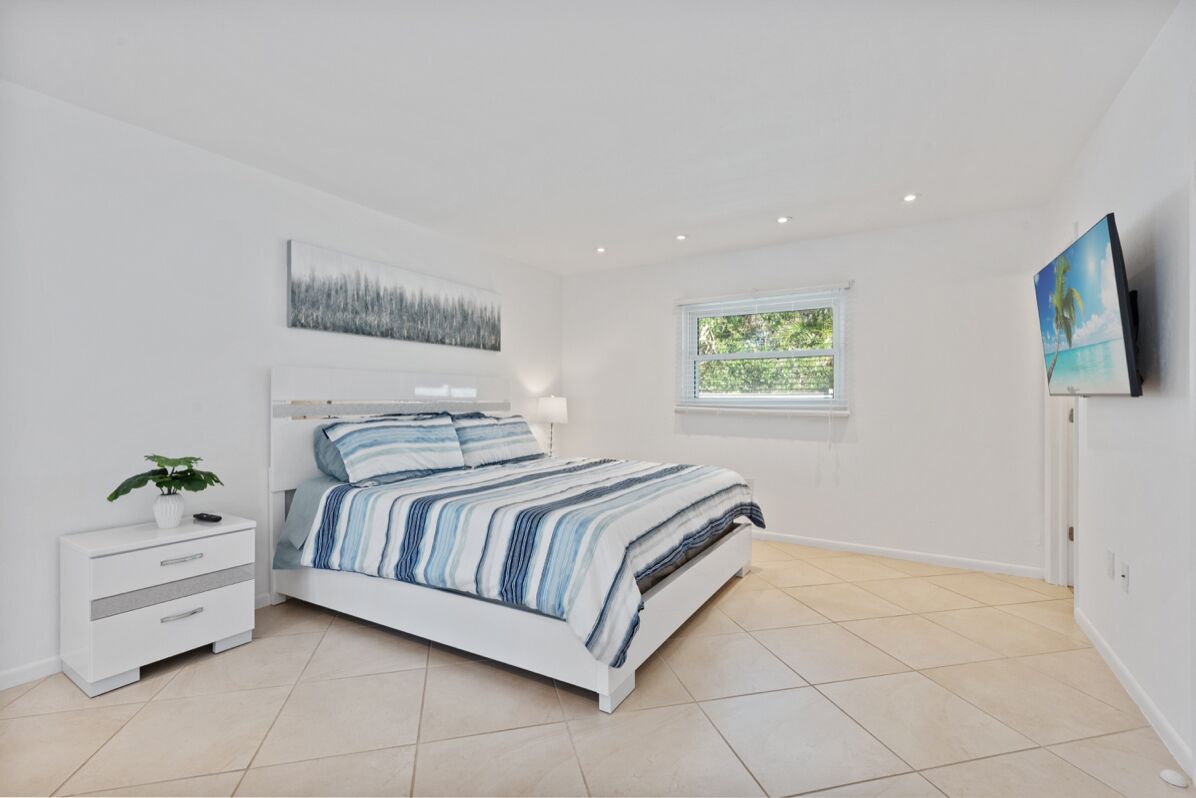 Una camera da letto con un letto, un comodino, una finestra e un quadro appeso al muro.