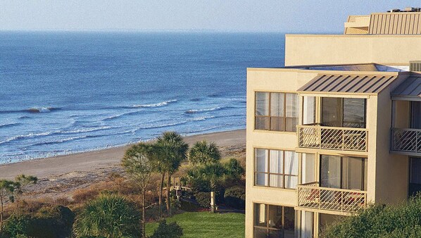 A beachfront building with multiple balconies overlooking the ocean.