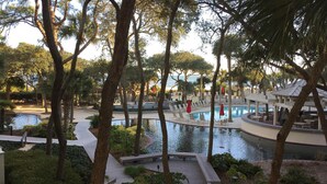 A resort pool area with lounge chairs and a small water feature surrounded by trees.