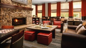 Un rincón de estar acogedor con chimenea de piedra, asientos de cuero y una mesa de comedor.