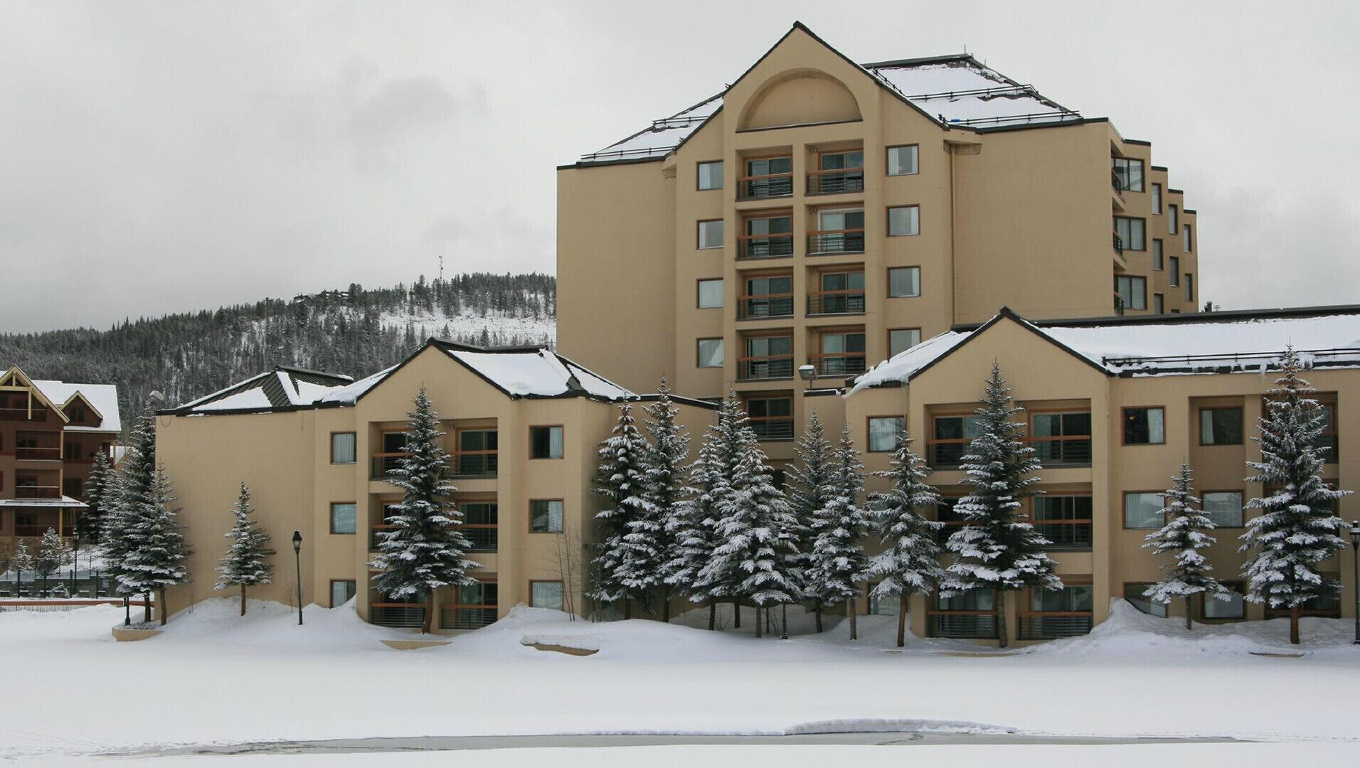 A multi-story hotel with a symmetrical facade, large windows, and a snow-covered roof.