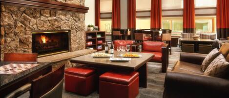 A cozy lounge area with a stone fireplace, leather seating, and a dining table.