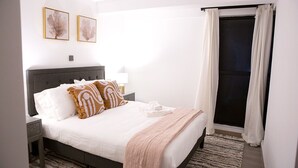Une chambre bien rangée, avec un lit, des tables de chevet et une fenêtre avec des rideaux.