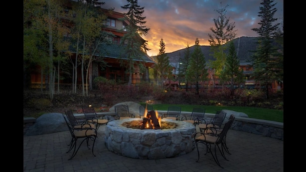 A stone fire pit with chairs around it, set in a landscaped area with trees and a building in the background. - 1 Bedroom Deluxe - Located within Marriott's Grand Residence Club, Lake Tahoe - Full Resort Access (South Lake Tahoe)