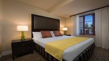 Une chambre d’hôtel avec un grand lit, deux tables de chevet avec des lampes, une fenêtre avec des rideaux et une vue sur l’extérieur.