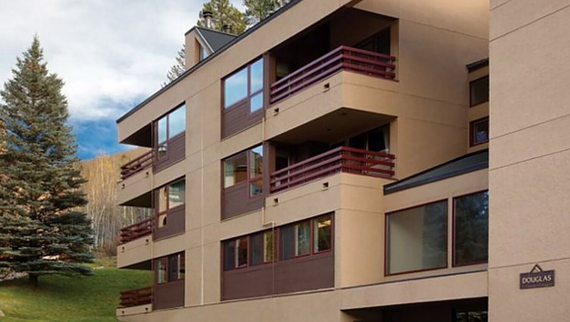 A multi-story building with balconies, large windows, and a sign that reads "Douglas".