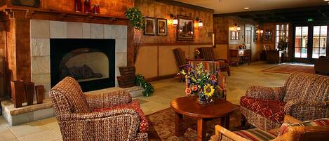 A cozy lobby with wicker furniture, a fireplace, and a floral centerpiece.