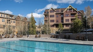 Un hotel con piscina, zona de estar al aire libre y montañas al fondo.