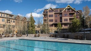 Un hotel con piscina, zona de estar al aire libre y montañas al fondo.