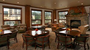 A spacious lounge area with large windows, a stone fireplace, and comfortable seating.