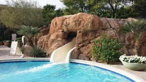 A pool with a rock formation and a slide.