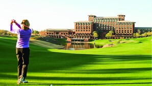A golf course with a large building in the background.