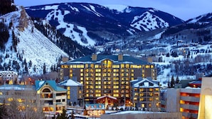 Un grand hôtel à étages, doté d’un atrium central, entouré de montagnes enneigées et situé à proximité d’une station de ski.