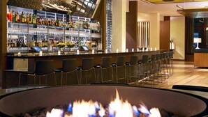 Un espace bar doté d’un long comptoir, de plusieurs étagères remplies de bouteilles et d’une rangée de tabourets de bar.