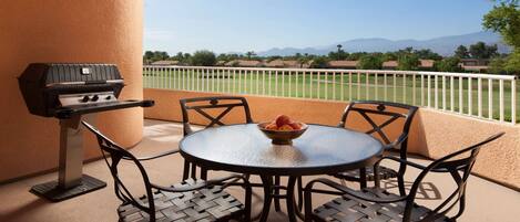 A patio with a grill, round table, and four chairs.