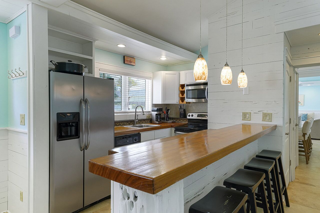 Una cocina moderna con refrigerador de acero inoxidable, una isla de madera e iluminación colgante.