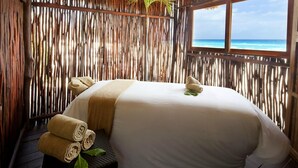 Una habitación con una cama, un ventanal con vista al océano y una pared de bambú.