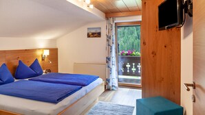 A bedroom with a bed, a TV, a window with curtains, and a view of greenery outside. - "Haus Alpenheim Apartment 1" with Mountain View, Balcony & Wi-Fi (Tux)
