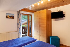 Une chambre à coucher comprenant un lit, une armoire, un téléviseur et une fenêtre donnant sur un paysage verdoyant.