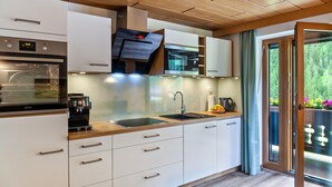 A modern kitchen with a built-in oven, a coffee machine, and a large window. - "Haus Alpenheim Apartment 1" with Mountain View, Balcony & Wi-Fi (Tux)