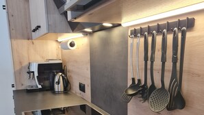 Una cocina moderna con estufa integrada, cafetera y un escurreplatos.