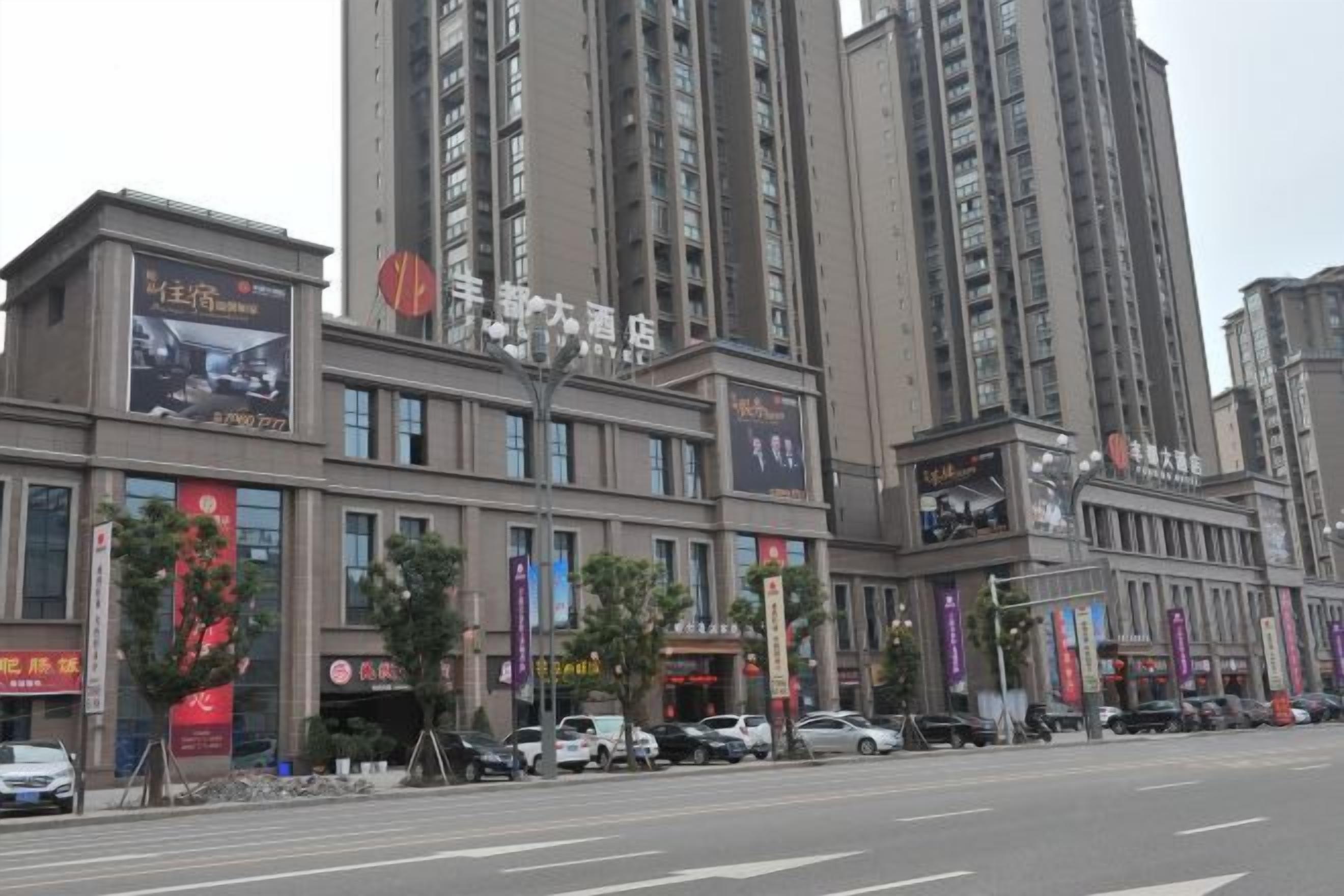 Een hotel met meerdere verdiepingen, grote ramen en diverse banners met advertenties voor verschillende diensten.