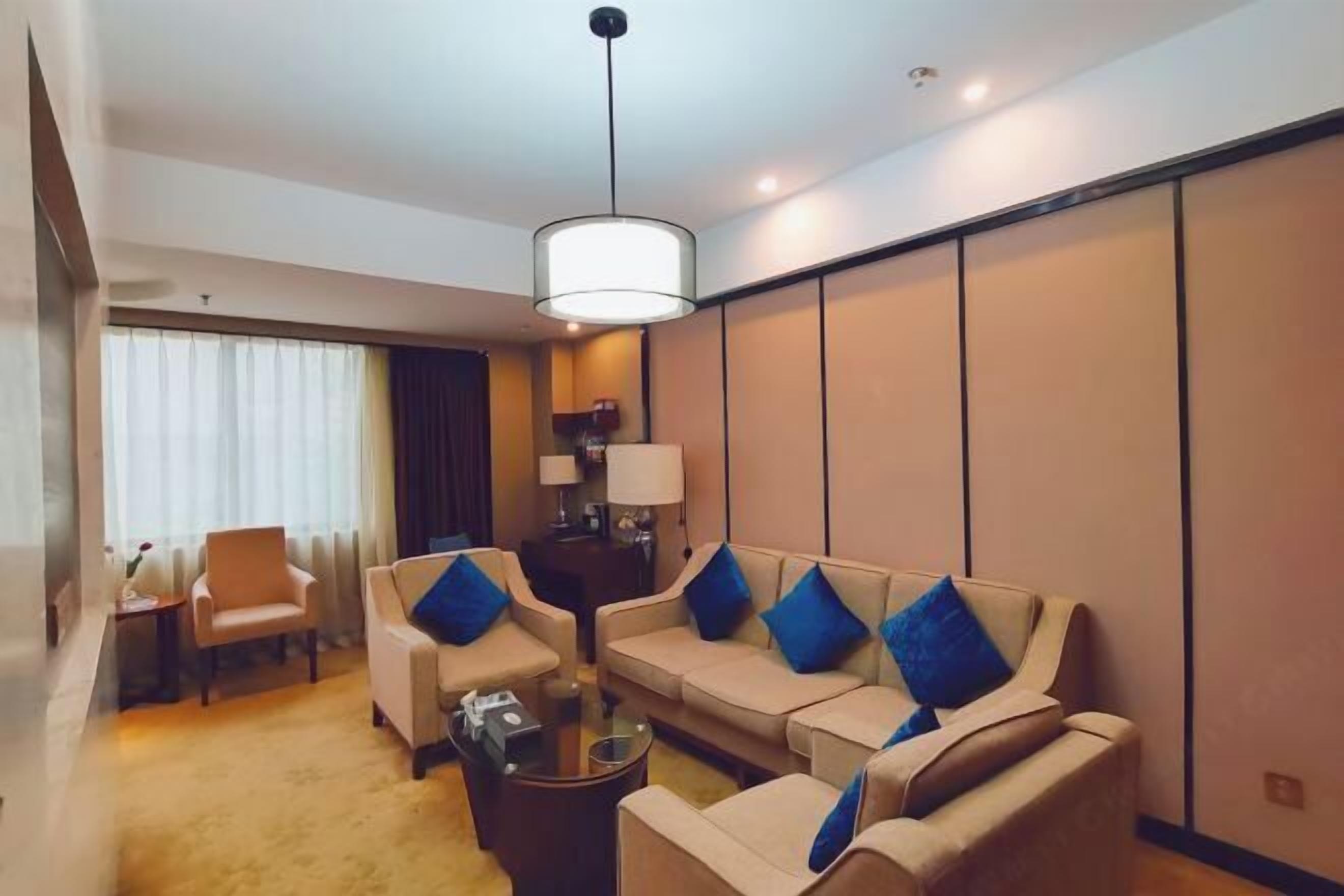 A modern hotel room with a sofa set, a coffee table, and a lamp.