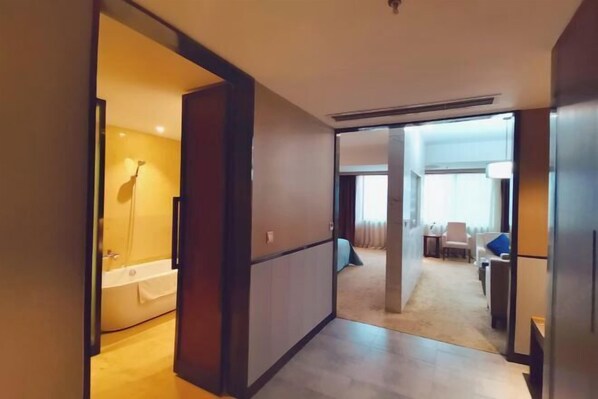 A hotel room with a bathtub, a dining area with a table and chairs, and a living area with a sofa. - Feng Du Hotel (Fengdu County)