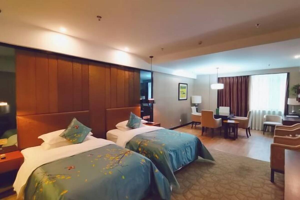 Habitación de hotel con dos camas, un escritorio, sillas y una televisión.