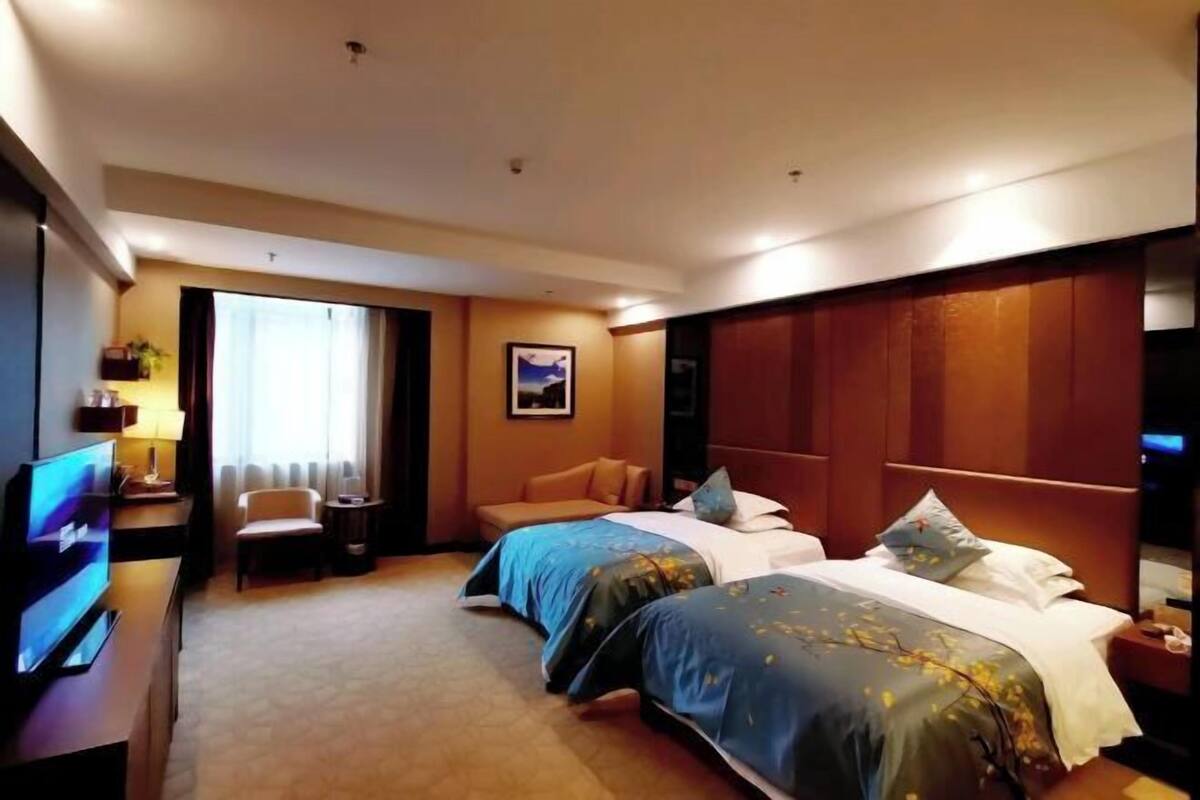 Una habitación de hotel con dos camas, televisión, escritorio y una silla.