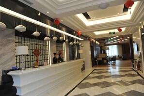 A hotel reception area with a marble counter, hanging pendant lights, and a check-in desk. - Feng Du Hotel (Fengdu County)