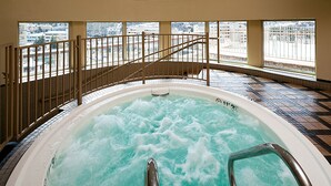 Un jacuzzi con vistas a un paisaje urbano nevado a través de amplios ventanales.