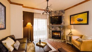 A cozy living room with a stone fireplace, a flat-screen TV mounted above it, and a comfortable sofa set.