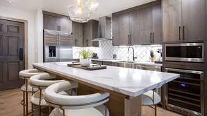 A modern kitchen with a large island, stainless steel appliances, and bar stools.
