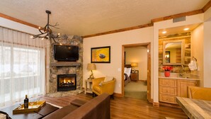 Un salon avec une cheminée en pierre, un téléviseur et un canapé.
