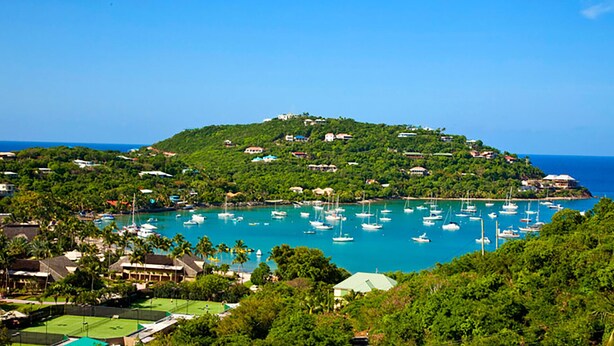 A coastal area with a hilltop village, clear blue waters, and numerous boats.