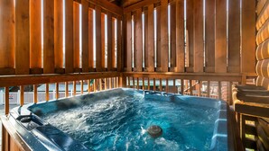 Ein Whirlpool mit umlaufender Holzterrasse, eingebettet in eine Holzhütte.