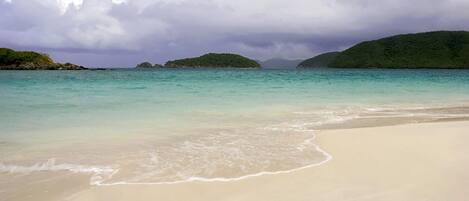 A beach with clear turquoise water and a sandy shore.