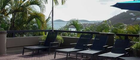 A rooftop pool area with lounge chairs and a view of the ocean.