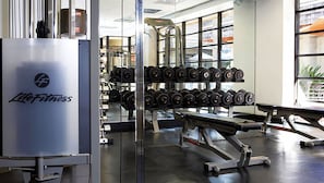 Un gimnasio con equipo de levantamiento de pesas, incluyendo mancuernas y bancos.