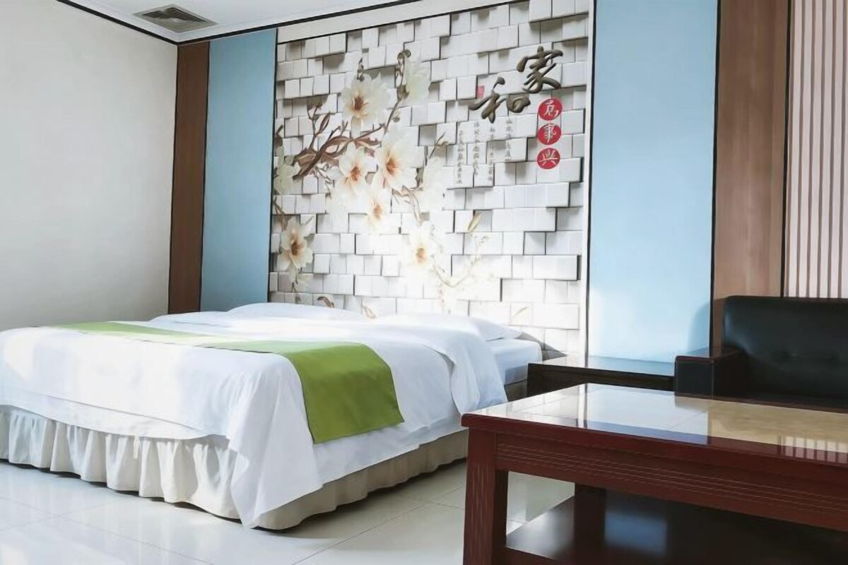 Una habitación de hotel con una cama, una mesita de madera y un panel decorativo en la pared.