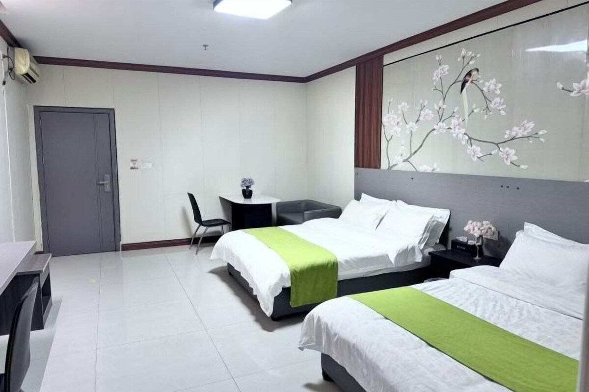 A hotel room with two beds, a desk, a chair, and a large window.