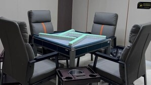 Un salón de conferencias con una mesa, cuatro sillas y un cesto de basura.