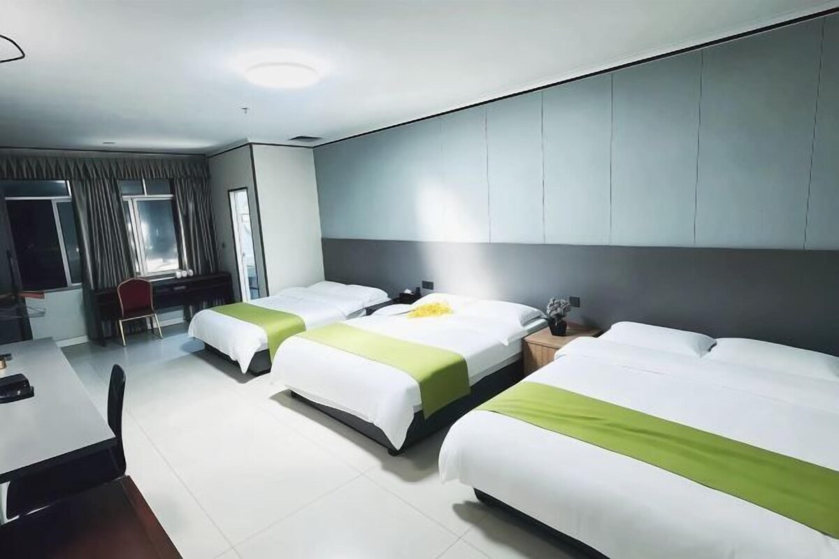 Una habitación de hotel con tres camas, un escritorio y una silla.