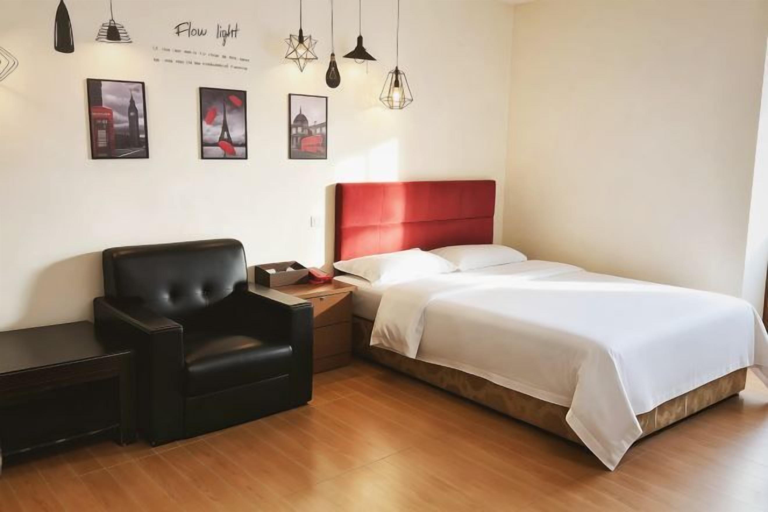 Een hotelkamer met een bed, een stoel, een nachtkastje en wanddecoratie.